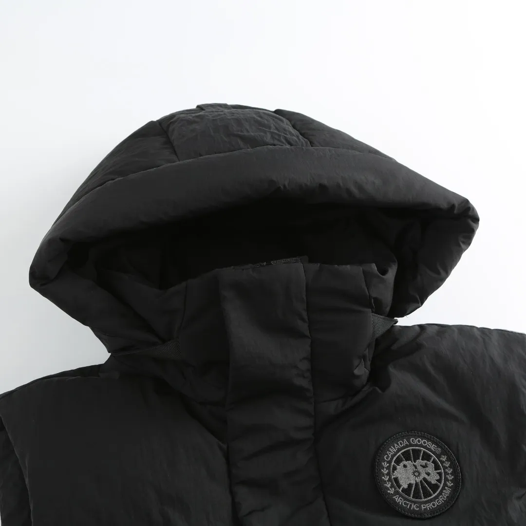 P740 Big Goose Logo Hooded Down Vest Fabric selection: The use of high-quality protective nylon fabric not only enhances the wear resistance of the surface, but also takes into account wind resistance, ensuring excellent performance in various harsh weather conditions.  90 national standard high-quality white duck down: selected high-loft down, weighing 170g, light and warm, with excellent temperature locking performance and good resilience.  Three-dimensional quilting process: Precision thread reinforcement to prevent velvet drilling and ensure that the fluffy and resilient elasticity lasts as new.  Details: Use polyester as the base for woven webbing, and use high-precision computer embroidery to decorate the brand letters on the webbing. The edges of the pattern are clear, the stitches are fine and even, and multiple layers of embroidery threads are stacked to enhance the three-dimensional effect. Accessories: One-to-one customized logo One-to-one customized zipper pendant One-to-one customized hem elastic buckle One-to-one customized snap button SIZE: S M L XL